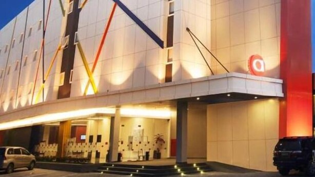 Un edificio moderno con un llamativo logotipo 'a' en la fachada, que presenta un diseño geométrico y limpio con techo plano y un amplio espacio de entrada.