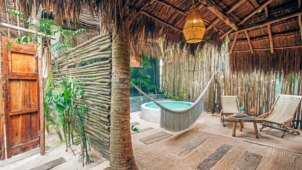 A thatched-roof room with a hammock, a wooden chair, and a small pool. - Solaya Boutique Hotel (Tulum)