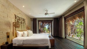 A spacious bedroom with a large bed, a ceiling fan, and a view of the outdoor area through a large window. - Solaya Boutique Hotel (Tulum)