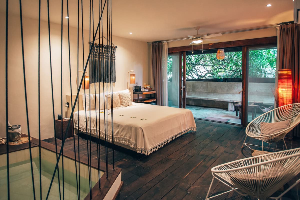 Ein Schlafzimmer mit Bett, Nachttischen, einer Pendelleuchte und Blick ins Freie.