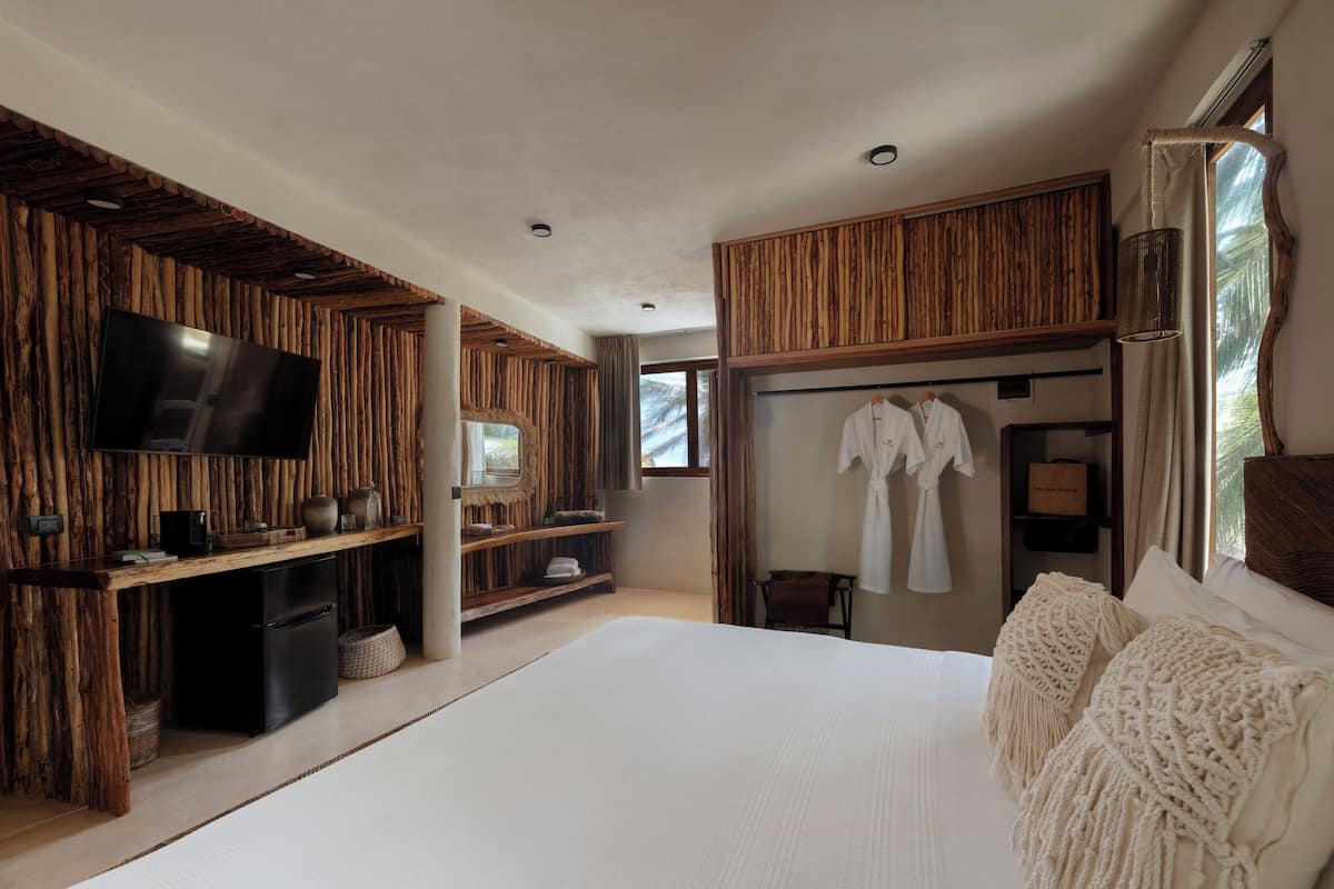 Ein modernes Schlafzimmer mit einem großen Bett, Holzpaneelen, einem Flachbildfernseher, einem Kleiderschrank und einem Fenster mit Vorhängen.