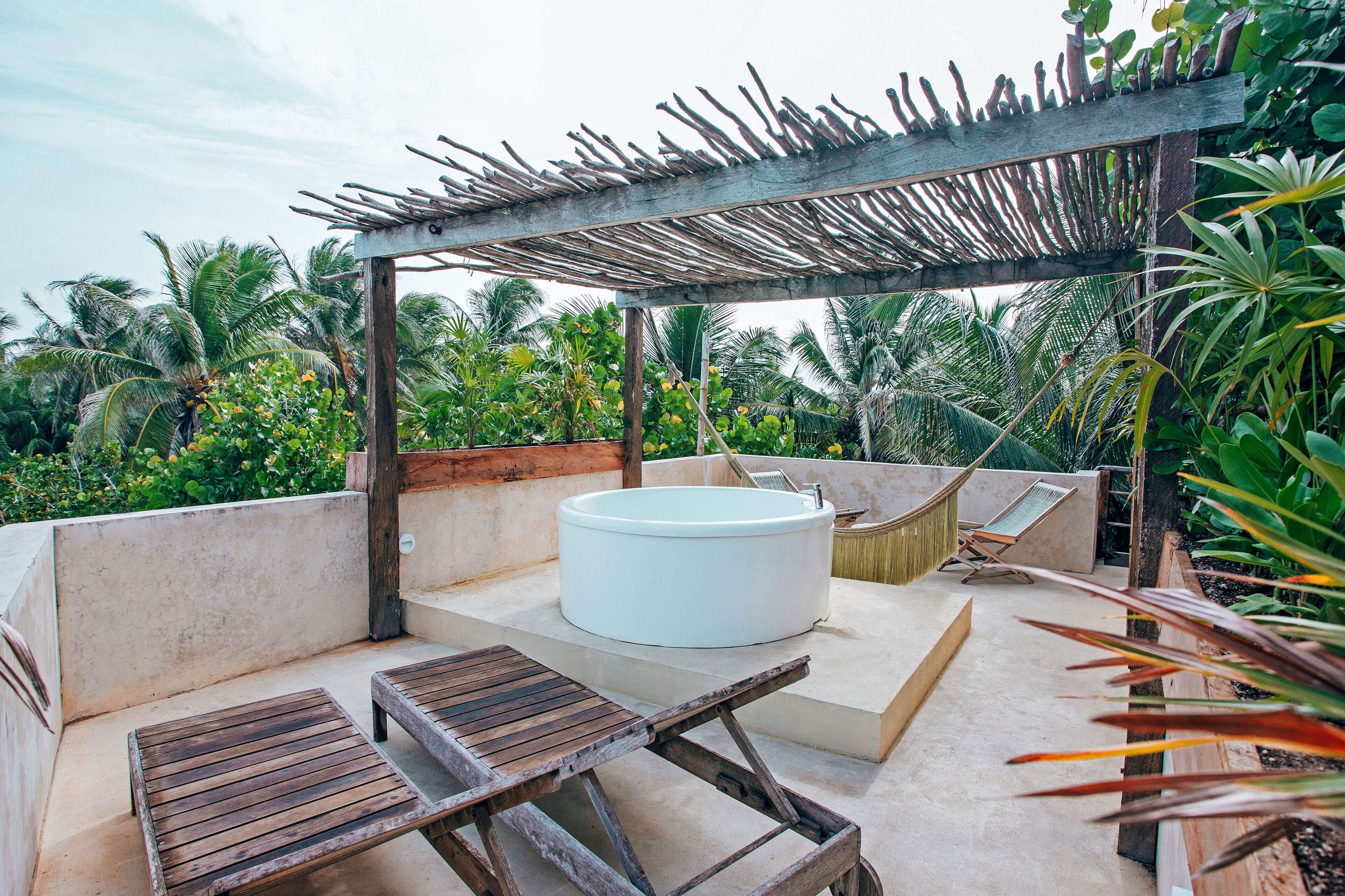 A rooftop terrace with a hot tub, wooden lounge chairs, and a pergola.