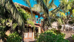 A tropical resort with a wooden staircase leading to a thatched-roof building, surrounded by lush palm trees and greenery. - Solaya Boutique Hotel (Tulum)