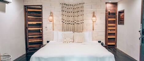 Quarto com cama grande, portas de madeira, ventilador de teto e luminárias na parede.