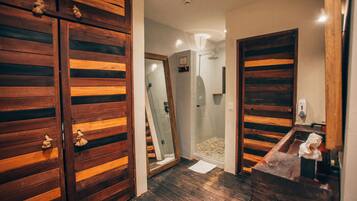 Een badkamer met houten deuren, een douche en een spiegel.