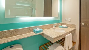 Un baño moderno con un espejo grande, un lavabo y un inodoro. Hay toallas y artículos de aseo en la encimera.