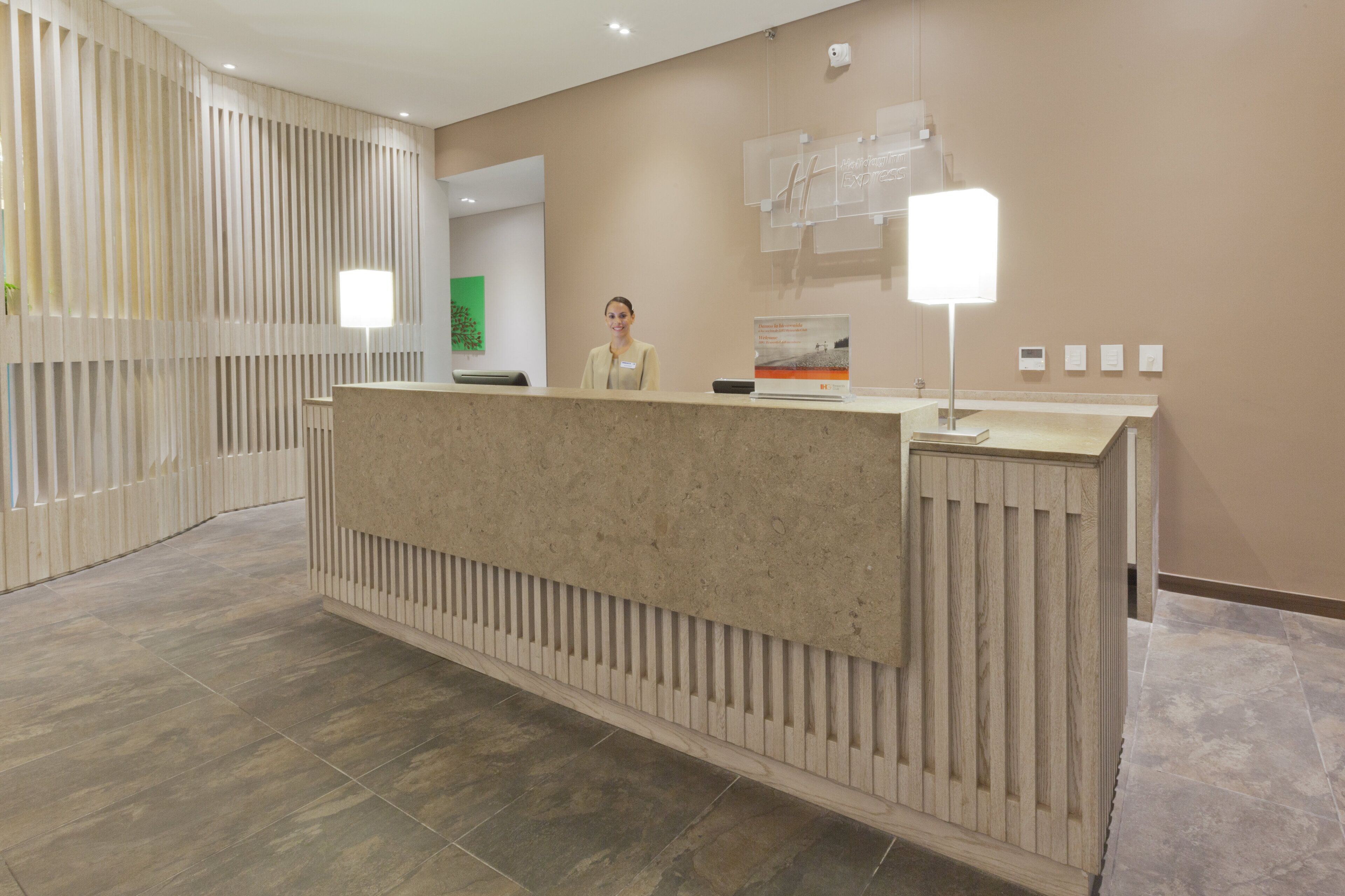 A reception desk with a modern design, a nameplate, and a sign for Holiday Inn Express.