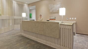 A reception desk with a modern design, a nameplate, and a sign for Holiday Inn Express.