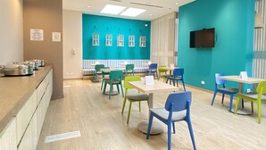 A modern dining area with teal walls, wooden tables, and colorful chairs. - Holiday Inn Express Yopal by IHG (Yopal)