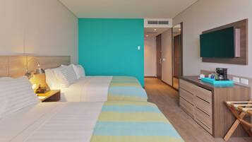 Habitación de hotel con cama, mesita de noche, lámpara y televisor montado en la pared.