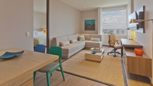 A modern hotel room with a sofa, a dining table, a chair, a coffee table, and a TV mounted on the wall. - Holiday Inn Express Yopal by IHG (Yopal)