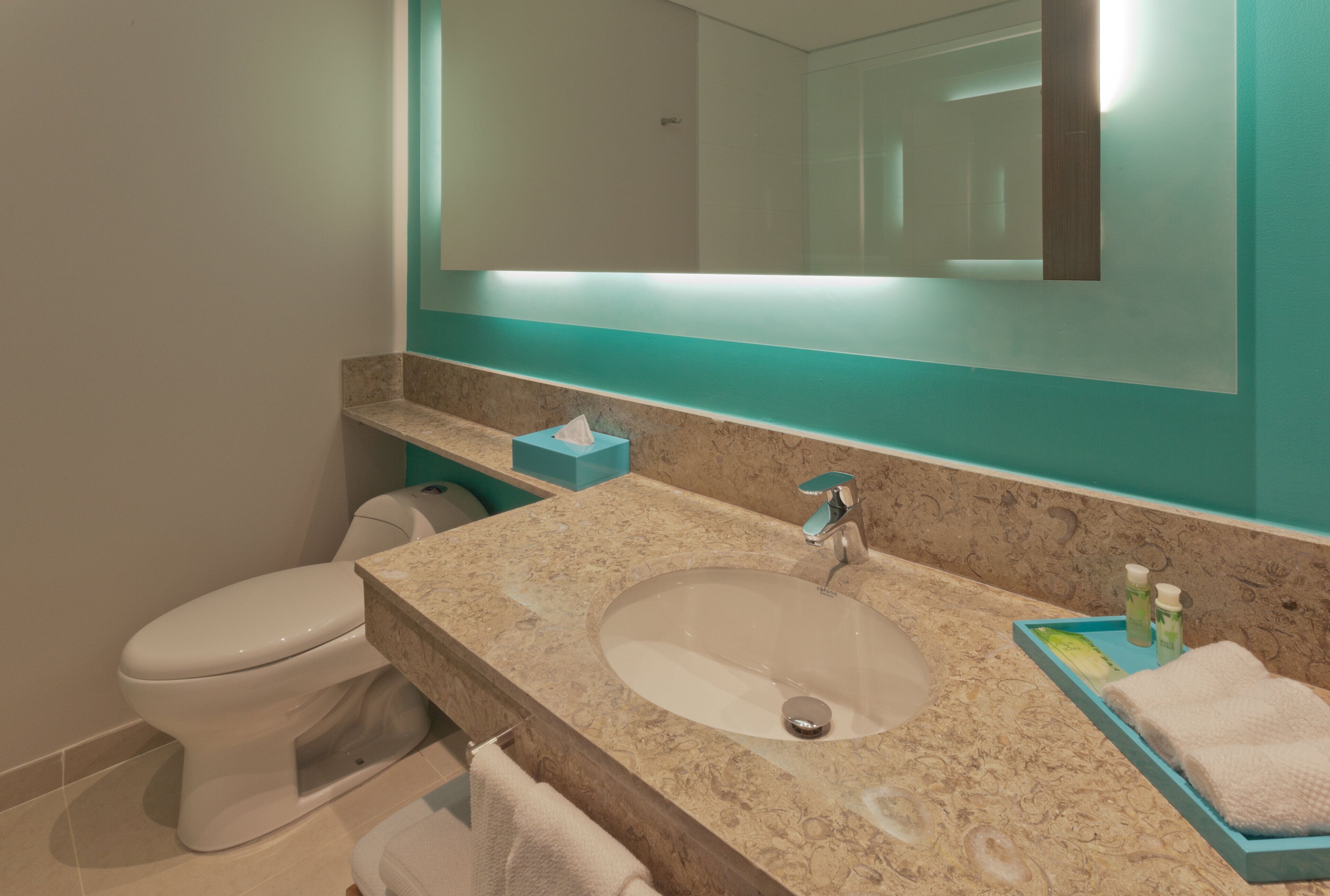 A bathroom with a toilet, sink, and mirror.