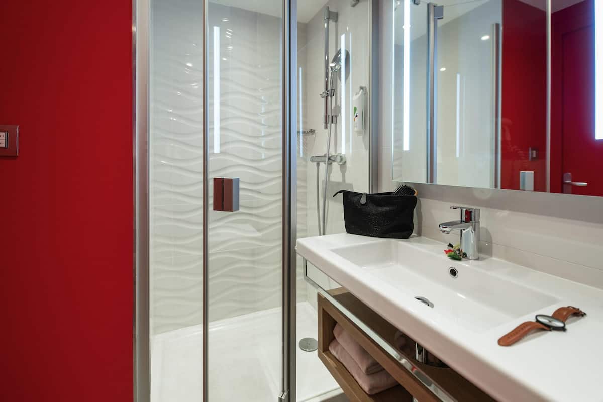 Un baño moderno con cabina de ducha de vidrio, un lavabo blanco y un espejo encima.