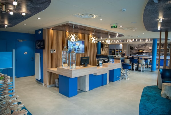 A reception area with a wooden counter, blue walls, and a bar area with stools.