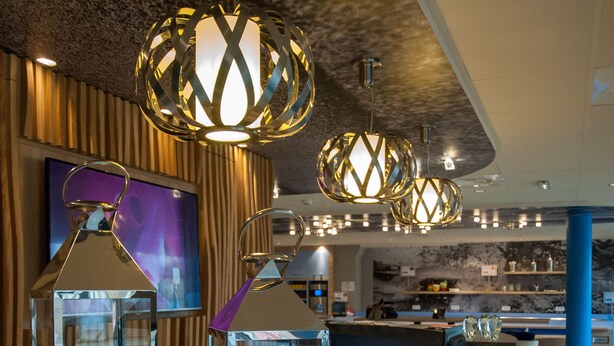 Un área de recepción moderna con un mostrador de madera, candelabros de cristal e iluminación colgante contemporánea.