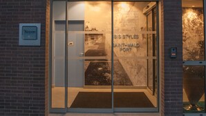 Un edificio con entrada de vidrio y un letrero de neón que dice "ibis styles".