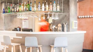 Una zona de bar con taburetes, una barra con botellas, vasos y una caja registradora.
