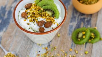 Un tazón de yogur cubierto con rodajas de kiwi, almendras y nueces picadas.