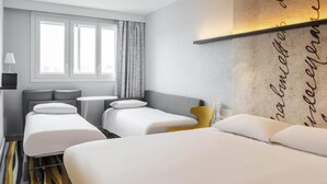 Habitación de hotel con dos camas, una mesita, una lámpara y una ventana con cortinas.