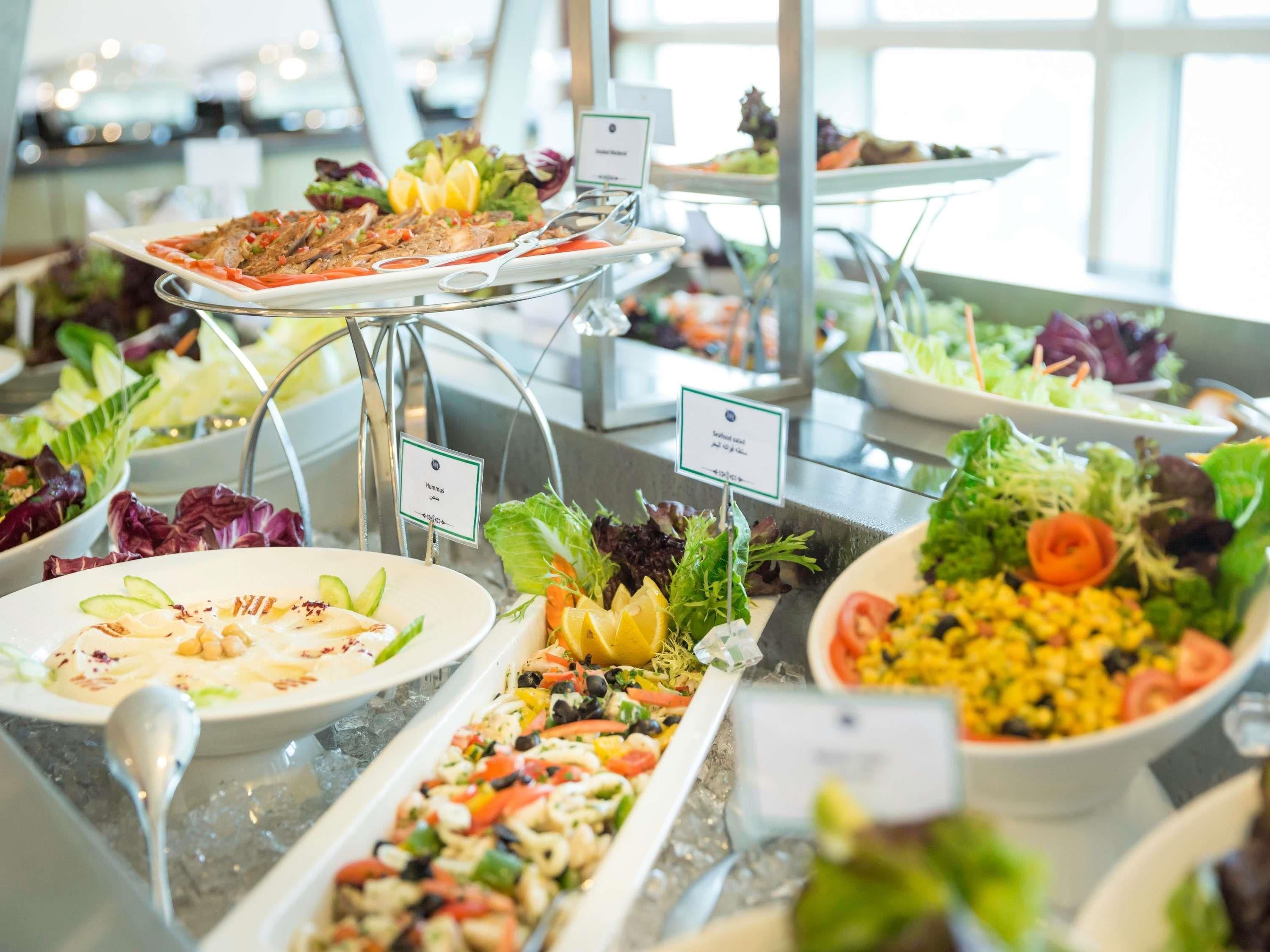 A buffet with various dishes including seafood salad, hummus, and a salad with corn and tomatoes.