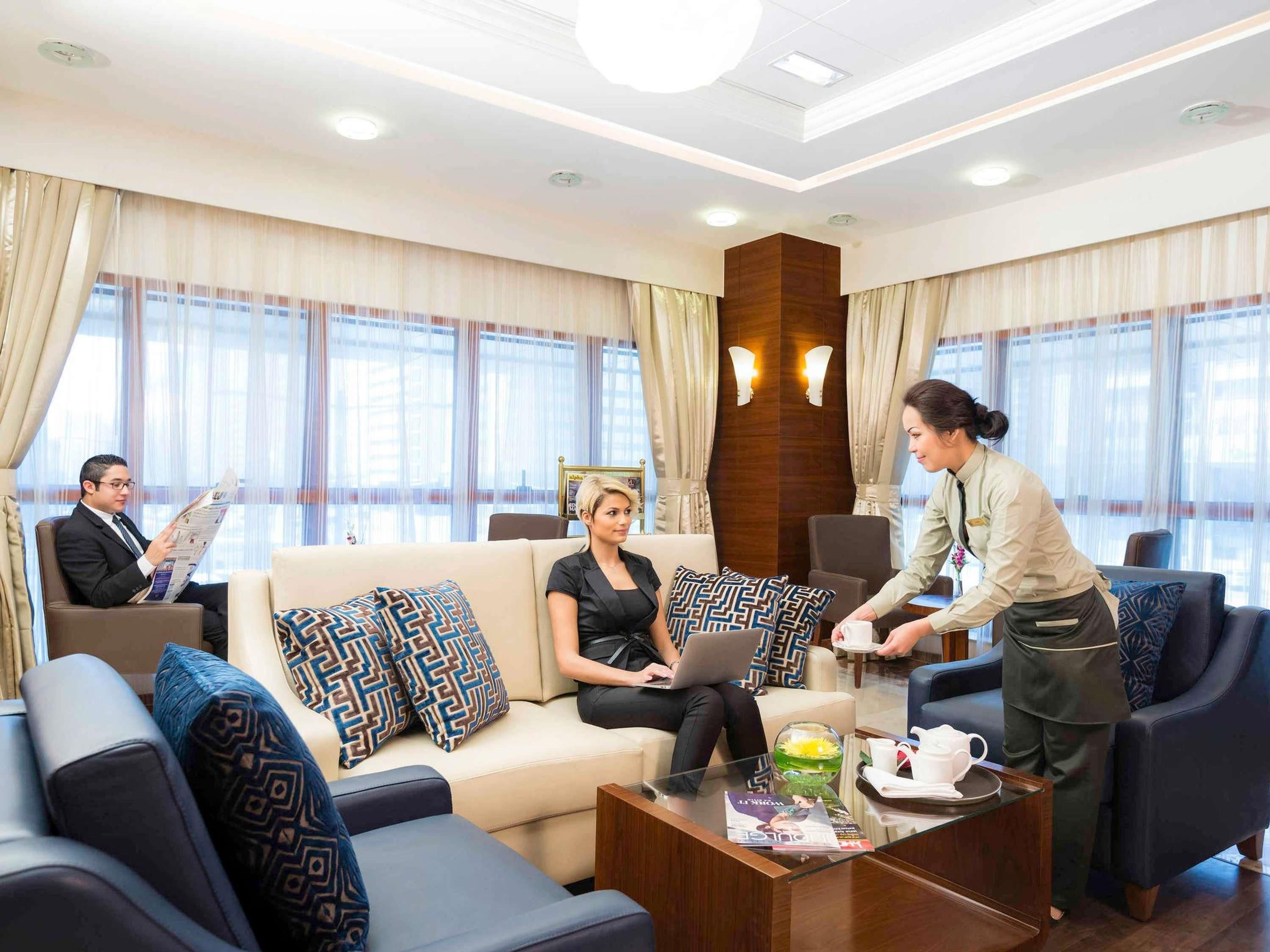 Um hall de hotel com sofá, cadeiras, mesa de centro e balcão de recepção.