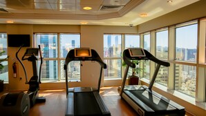 A gym with treadmills, a stationary bike, and a fire extinguisher. - Majlis Grand Mercure Residence Abu Dhabi (Abu Dhabi)