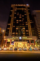 Un edificio alto con letreros iluminados que indican Majlis Grand Mercure Residence.