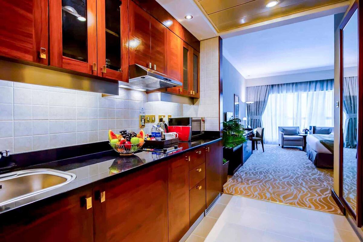 Una cocina de hotel moderna con armarios de madera, un frutero y un comedor con vistas.