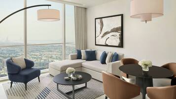 A modern living room with a sofa, armchairs, a coffee table, and a dining table. There is a large window offering a city view.