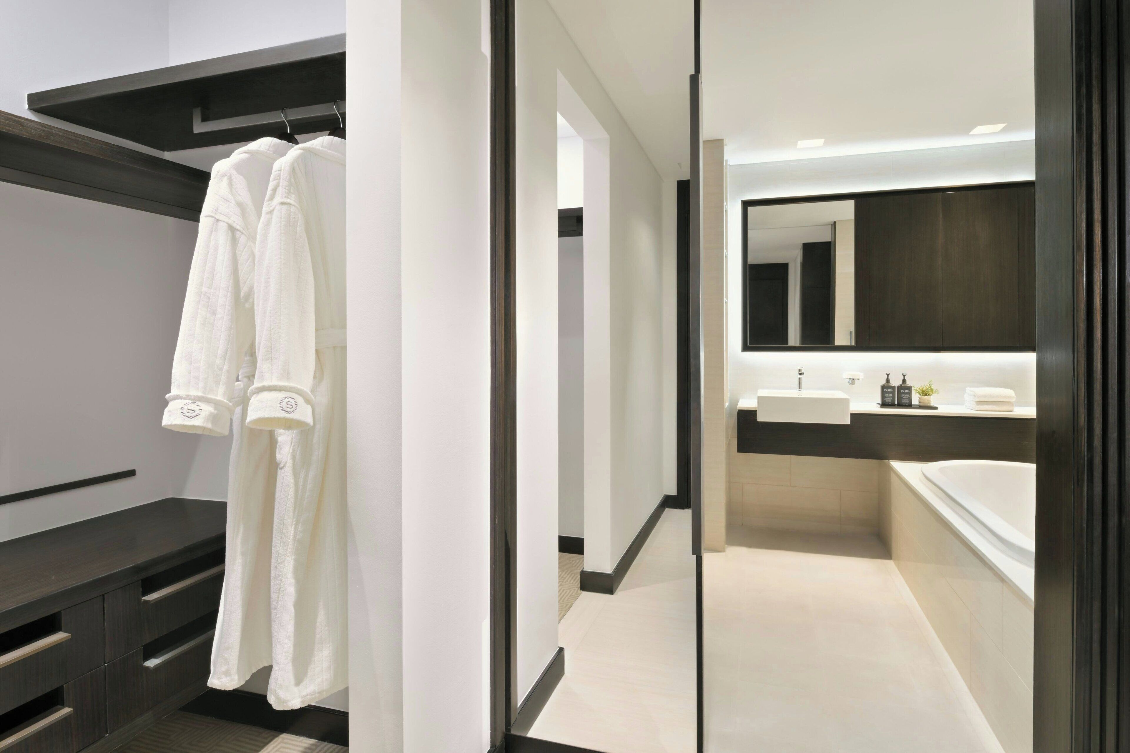 Un baño moderno con un espejo grande, una bañera y un tocador con lavabo.