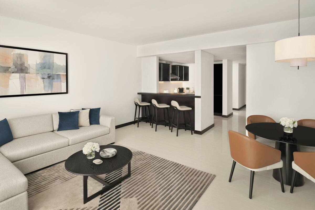 A modern living room with a sofa, coffee table, and dining area with chairs.