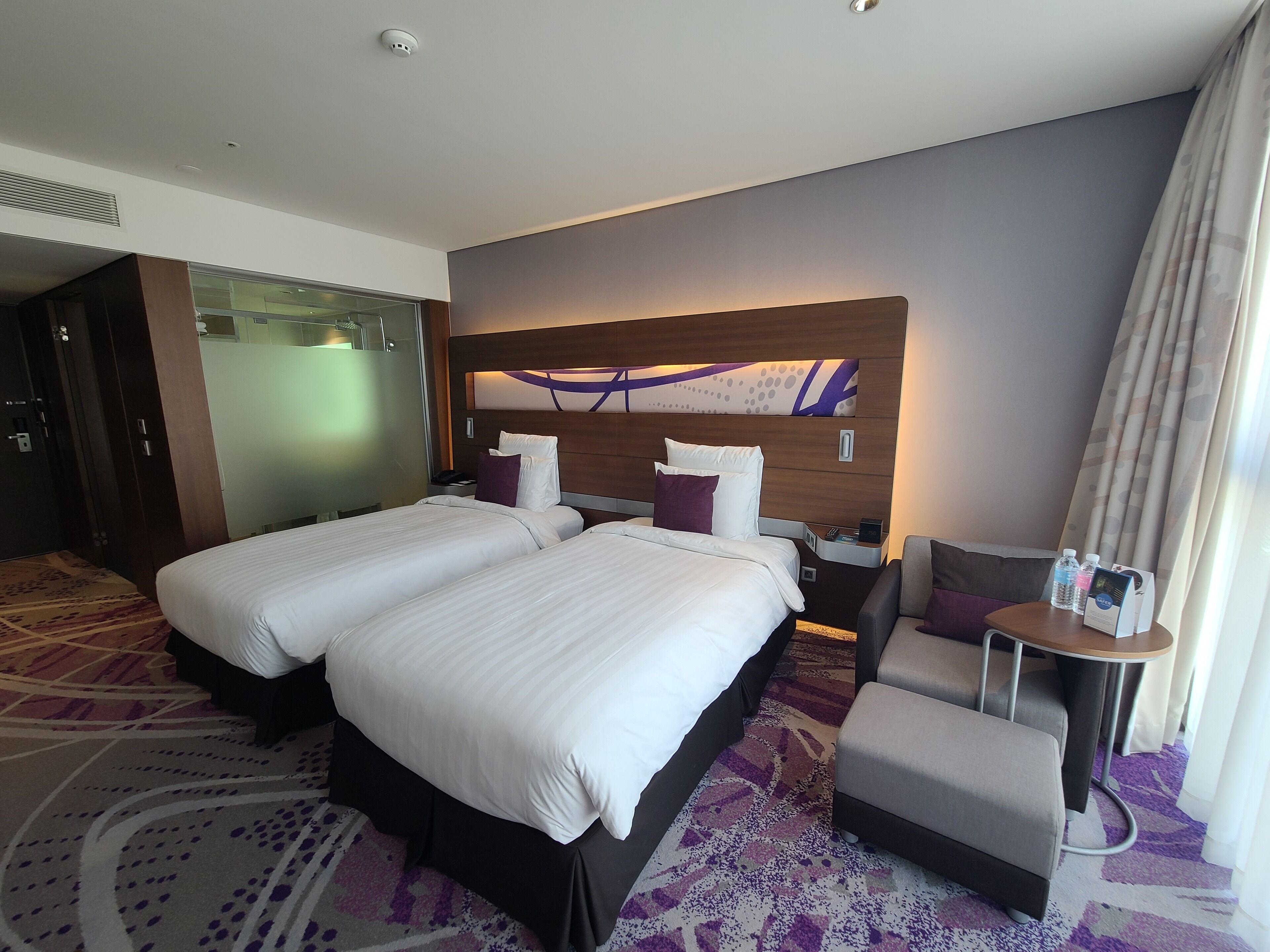 Una habitación de hotel con dos camas, una zona de estar y una obra de arte colgada en la pared.