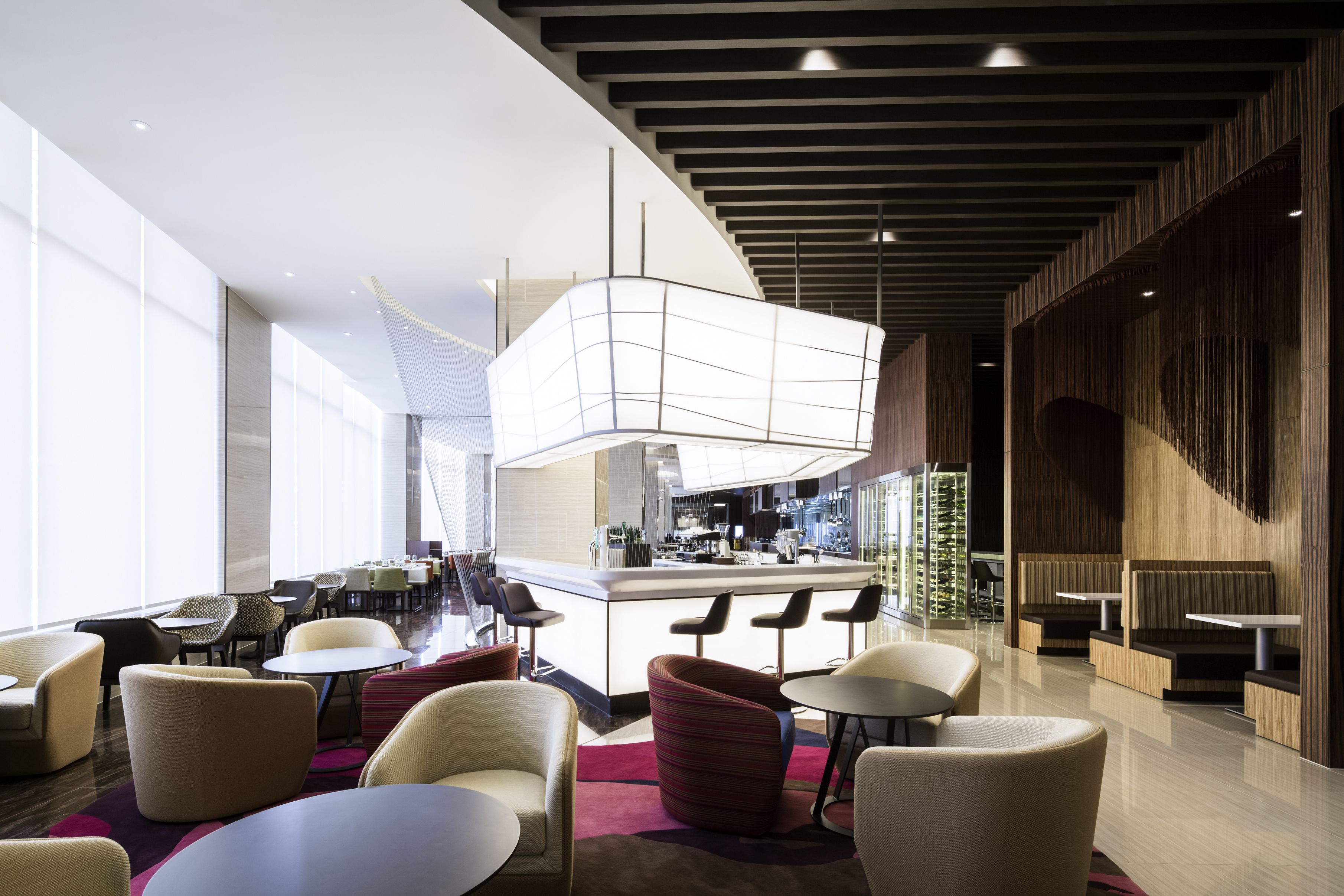 A modern hotel lobby with a bar area, seating arrangements, and a large window providing natural light.