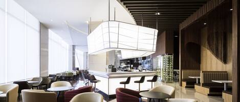 A modern hotel lobby with a bar area, seating arrangements, and a large window providing natural light.