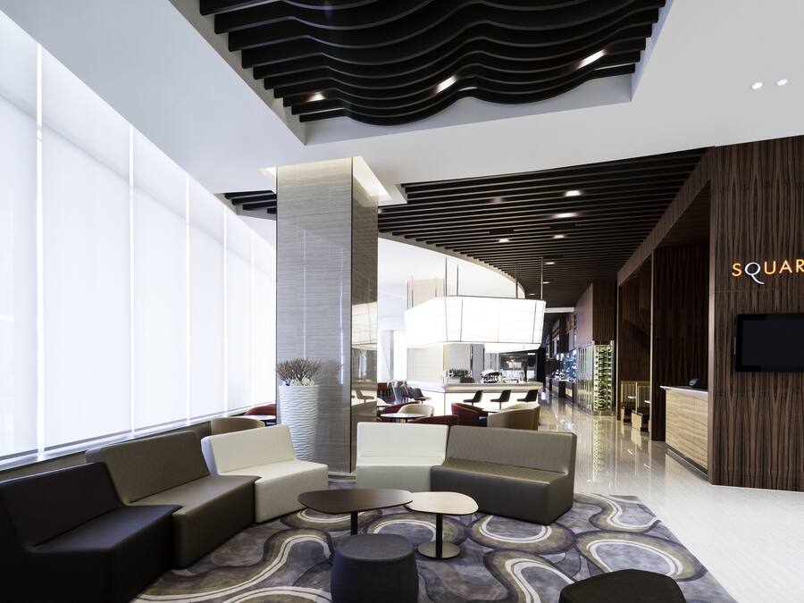 A modern lobby with seating areas, a reception desk, and a large window providing natural light.