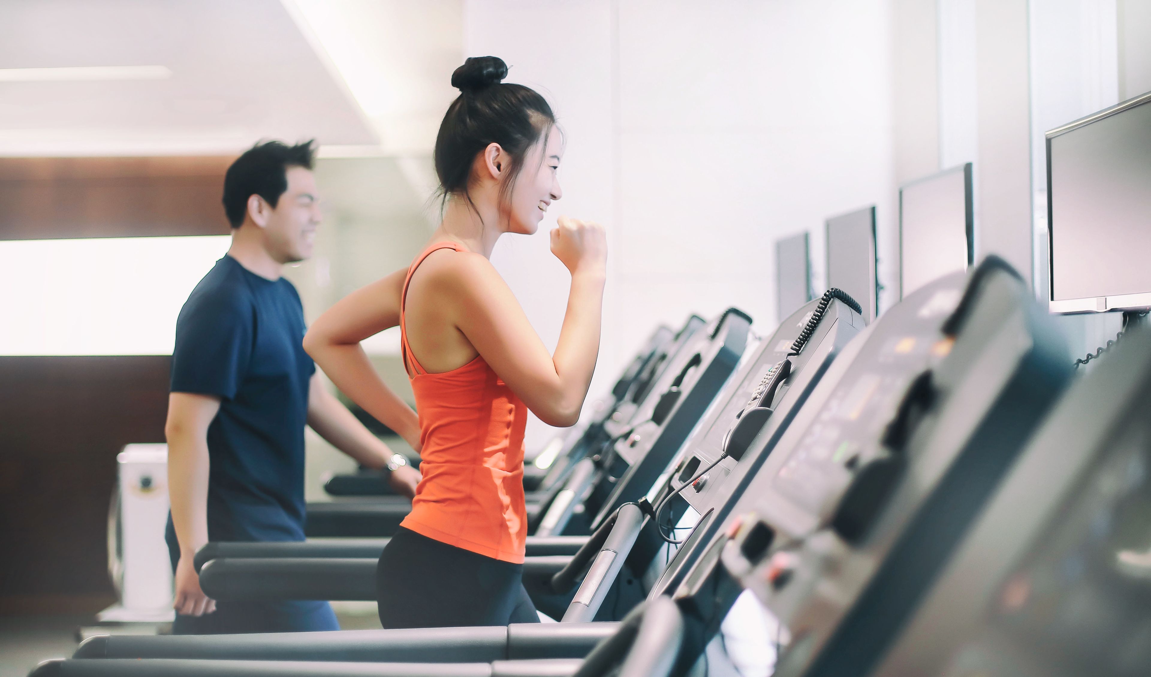 A gym with treadmills and a person running.
