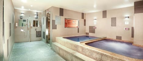 A modern spa area with a hot tub, a separate steam room, and a shower area.