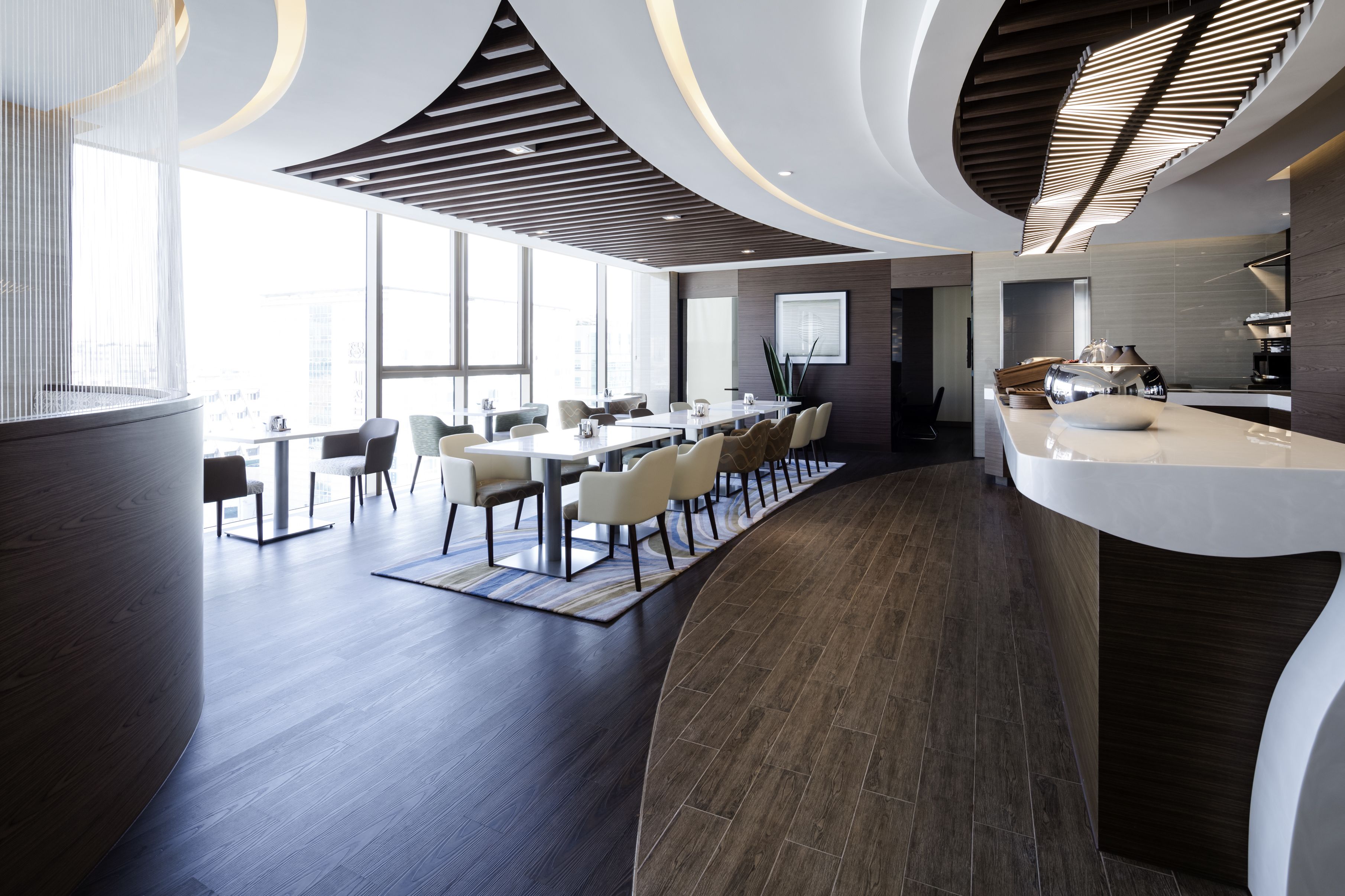 A modern conference room with a long table, chairs, and a kitchen area.