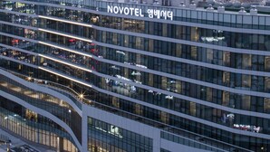Un hotel moderno con fachada de vidrio, varios pisos y una entrada destacada.