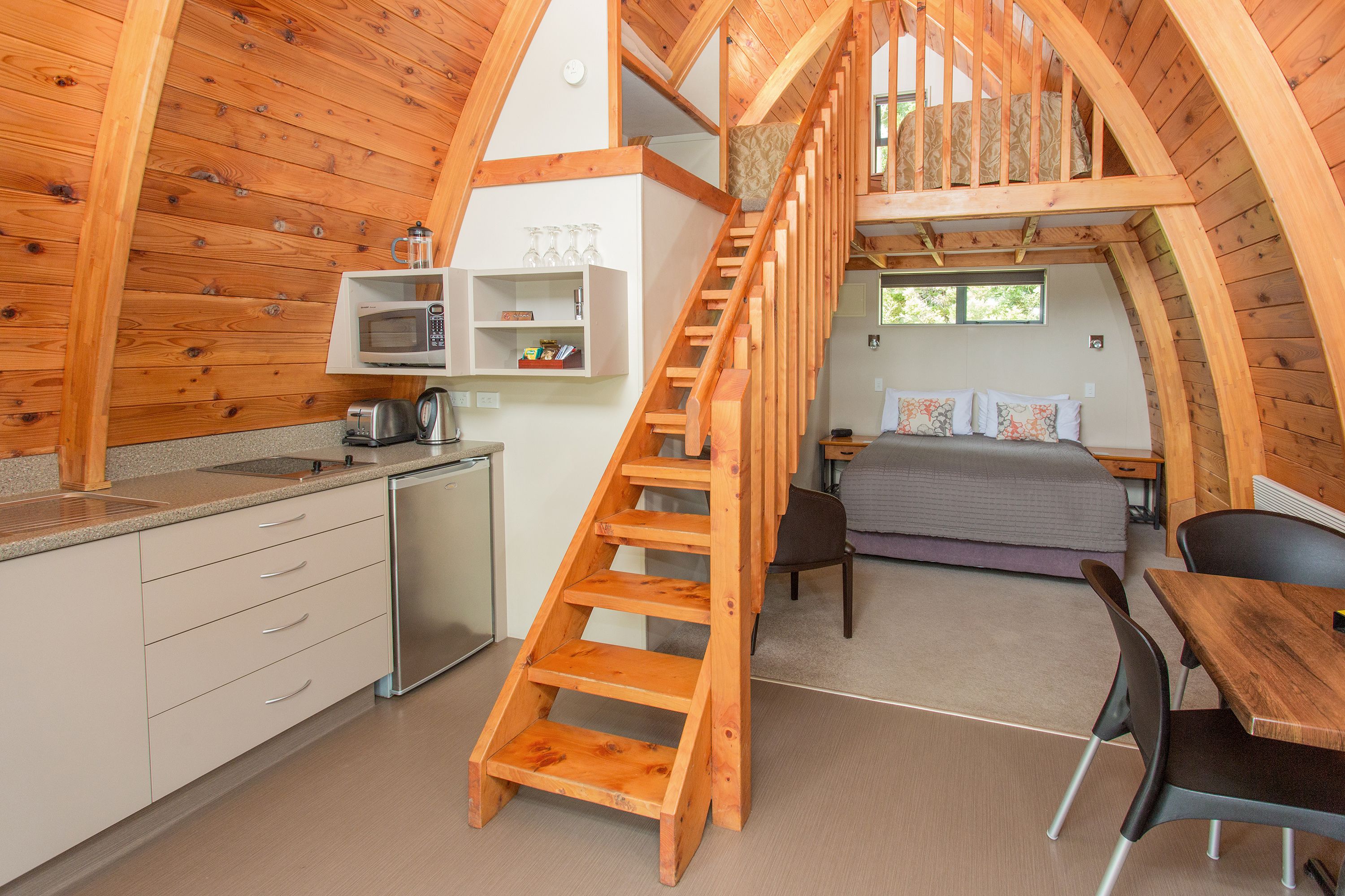 Eine kleine, hölzerne Hütte mit Küche, Essbereich und Schlafzimmer im oberen Bereich.