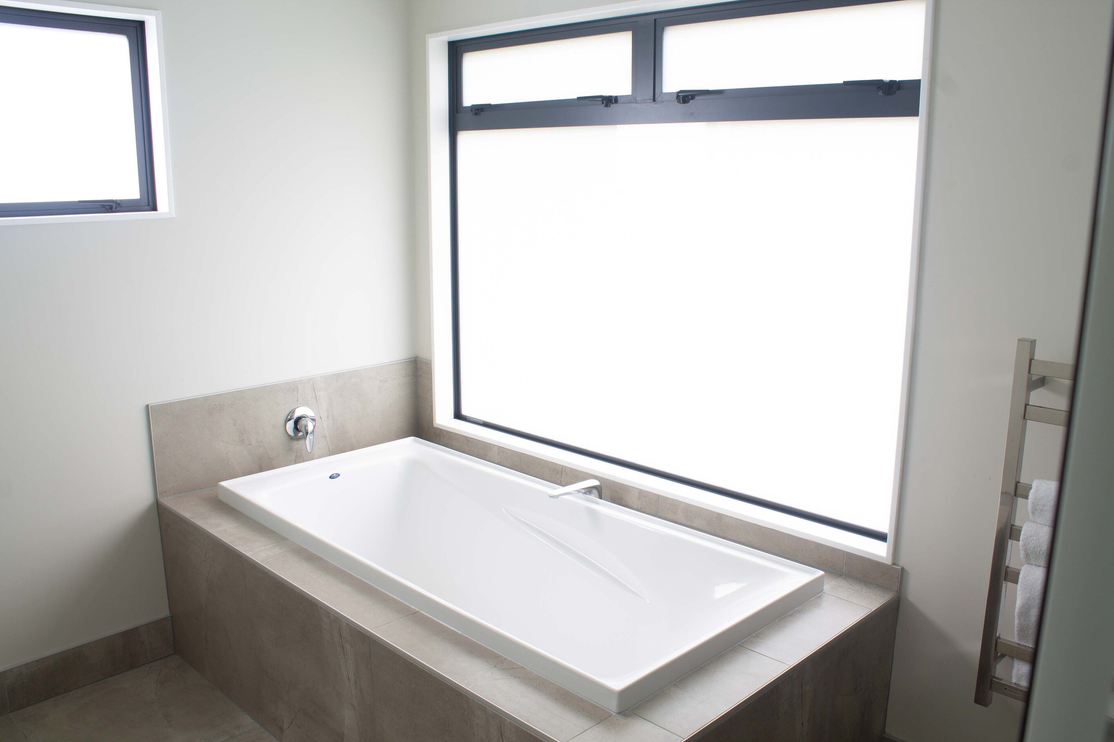 Un baño moderno con una bañera independiente, una ventana y un perchero para toallas.