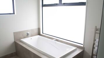A modern bathroom with a freestanding bathtub, a window, and a towel rack.