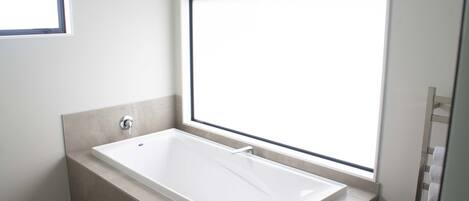 Un baño moderno con una bañera independiente, una ventana y un perchero para toallas.