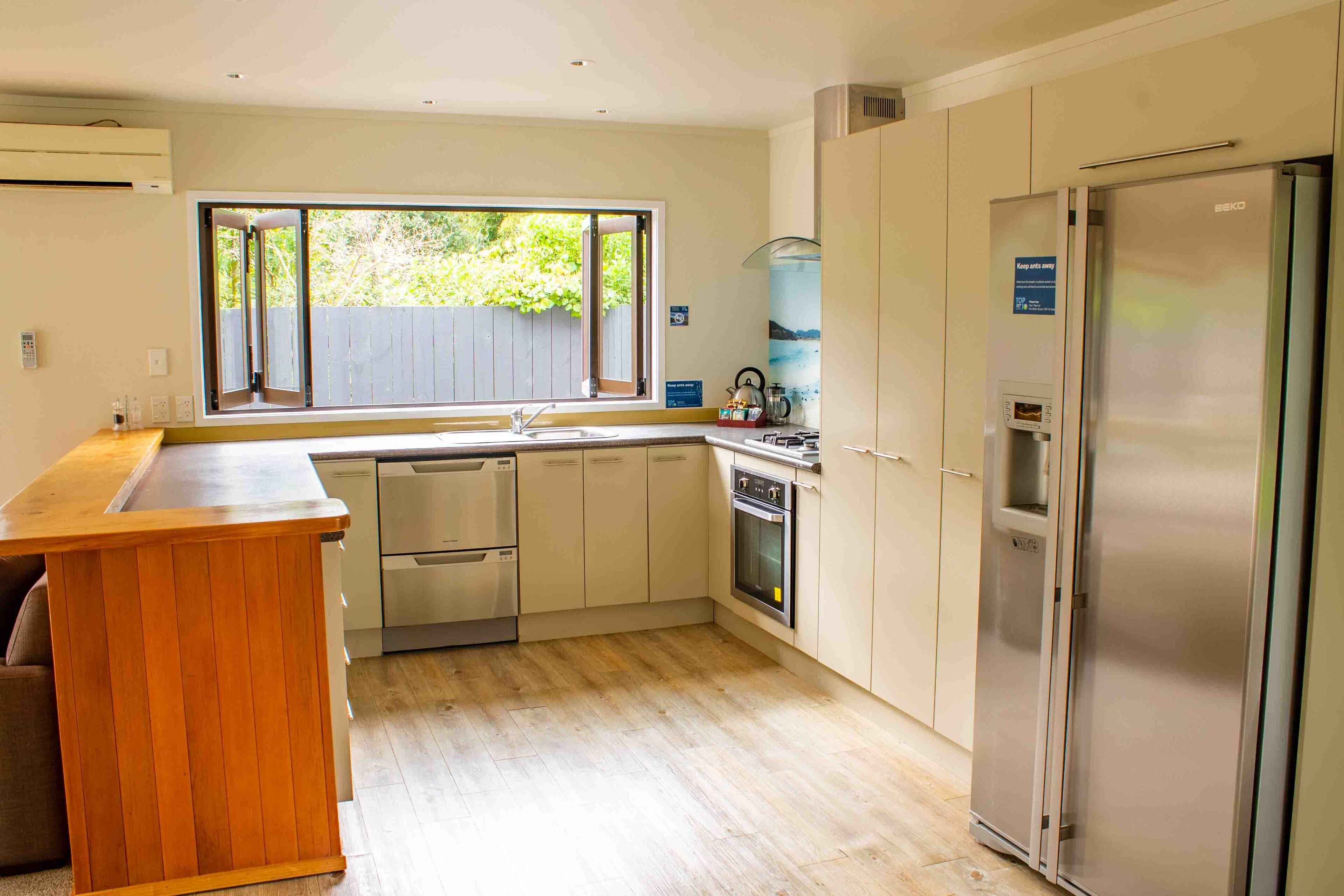 Een moderne keuken met een houten kookeiland, roestvrijstalen apparatuur en een groot raam dat voor natuurlijk licht zorgt.