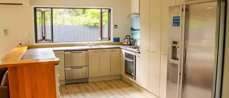 Een moderne keuken met een houten kookeiland, roestvrijstalen apparatuur en een groot raam dat voor natuurlijk licht zorgt.