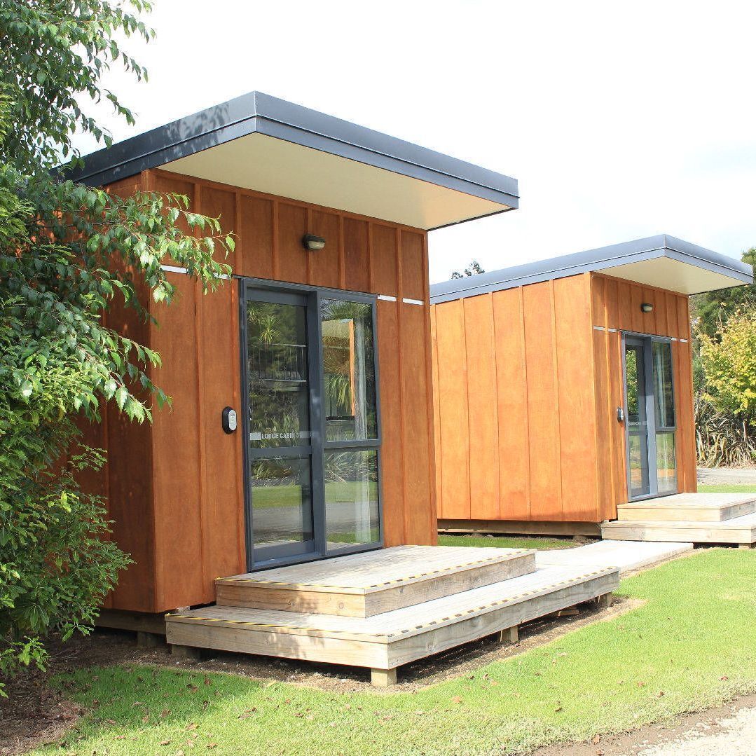 A modern lodge cabin with a wooden exterior, glass doors, and a flat roof.