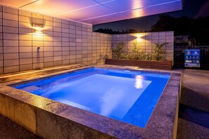 Piscina rectangular con agua cristalina azul, rodeada por un muro de azulejos e iluminada por luces empotradas.