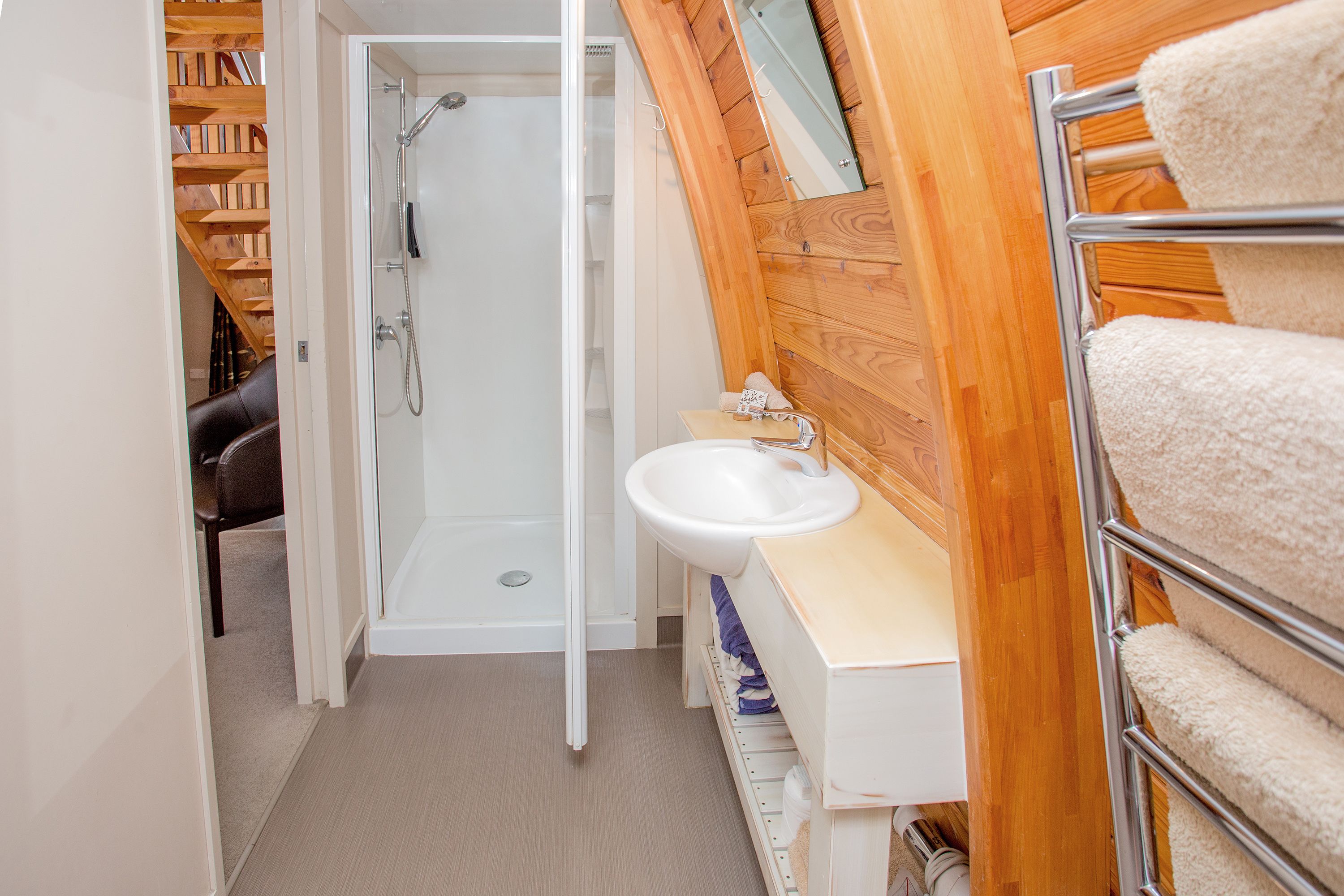 A bathroom with a shower, sink, and towel rack.