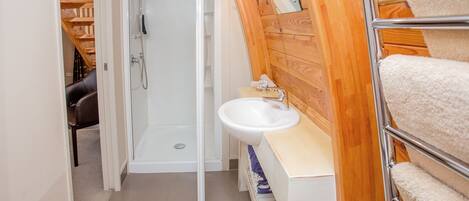 A bathroom with a shower, sink, and towel rack.