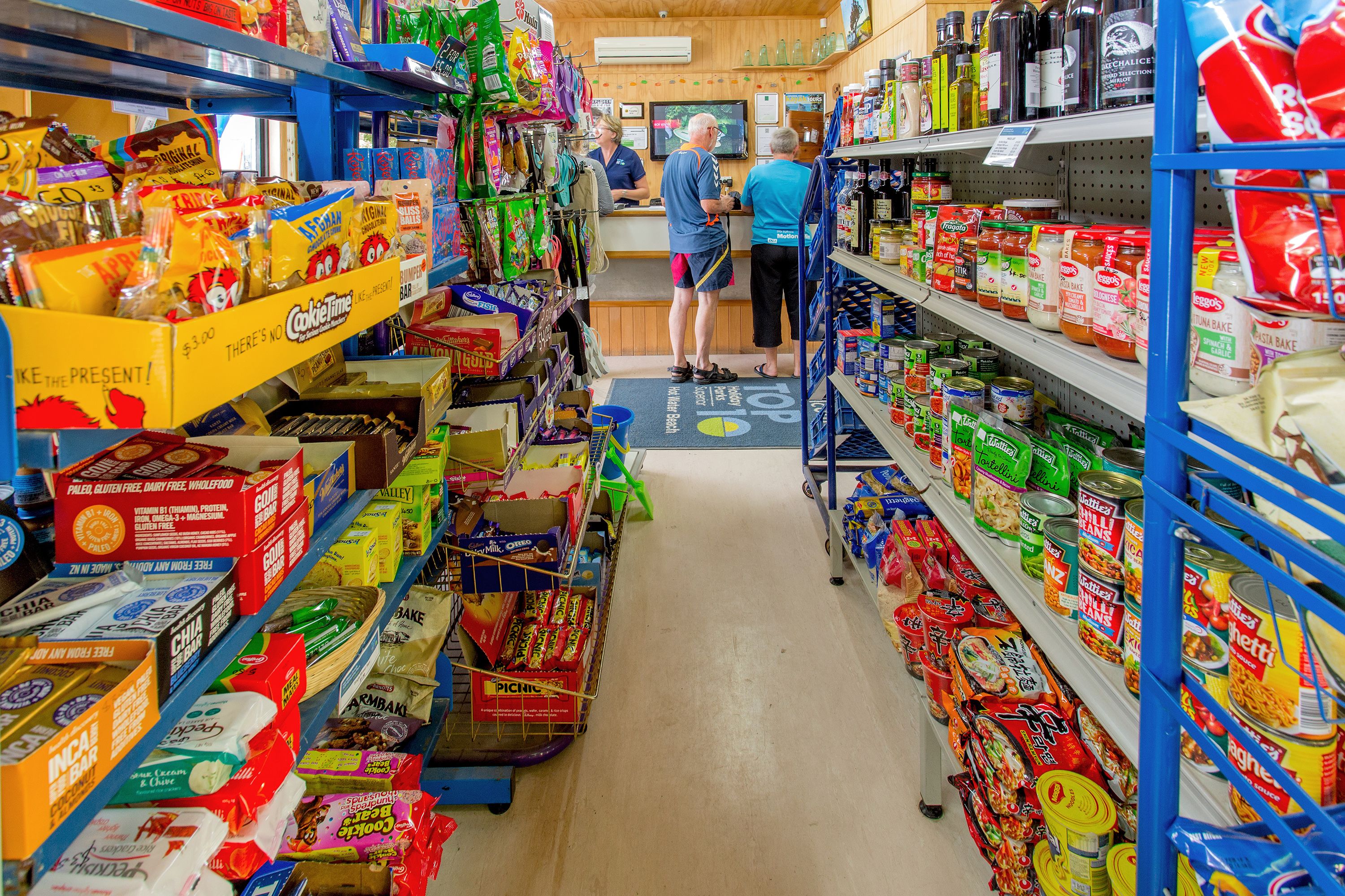 Un corridoio di un supermercato con diversi prodotti alimentari confezionati e una cassa.